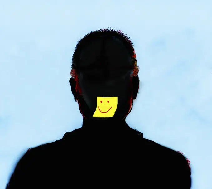 Yellow sticky note with smiley face on silhouette of man's face