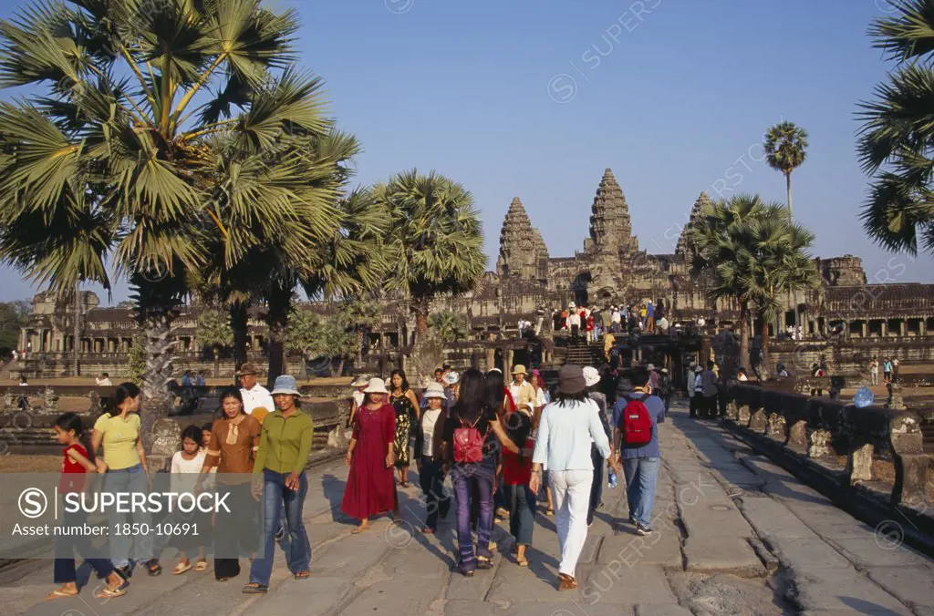 Cambodia, Siem Reap Province, Angkor Wat, Tourists On Tree Lined Stone Causeway Leading To Temple Complex.  Many Cambodians Visiting During Chinese New Year.