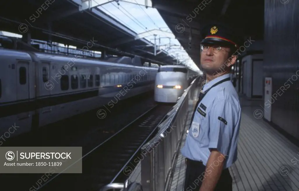 Japan, Honshu, Kyoto, Bullet Train Aka Shinkansen Pulling Into The Station Platform With Train Guard Standing In The Foreground