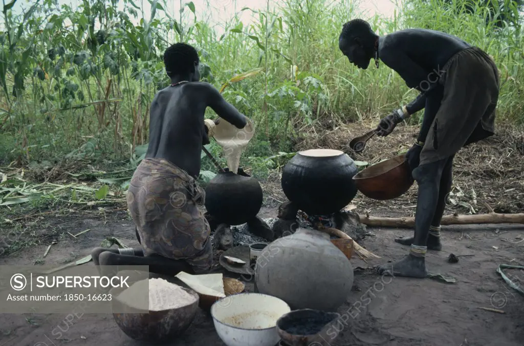 Sudan, Tribal People, Dinka Women Cooking Millet And Sorghum In Pots Over Open Fire.