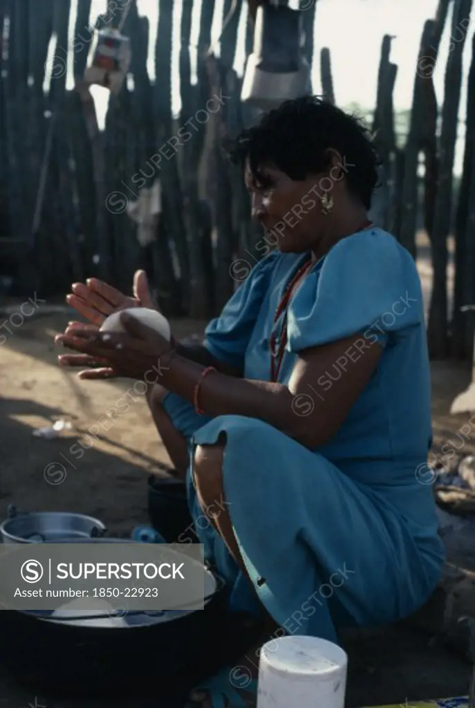 Colombia, Guajira Peninsula, Guajiro Indians, 'Guajira Indian Woman In The Process Of Making ''Arepas'' From Kneeded Maize Flour Dough, Over A Fire In Typical Open Shelter Desert Home. Wayu Wayuu Guajiro Amerindian Arawakan Colombia-Venezuela Border American Colombian Columbia Female Women Girl Lady Hispanic Latin America Latino South America '