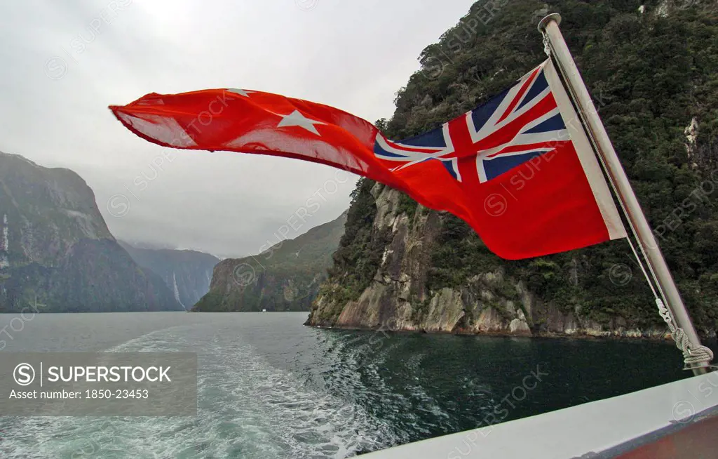 New Zealand, South Island, 'Milford Sound,', 'Southland, A New Zealnd Ensign Flag Waves On The Rear Of Real Journeys Cruise Boat The Milford Mariner As It Travels Along Milford Sound In New Zealands Fjordland Area'