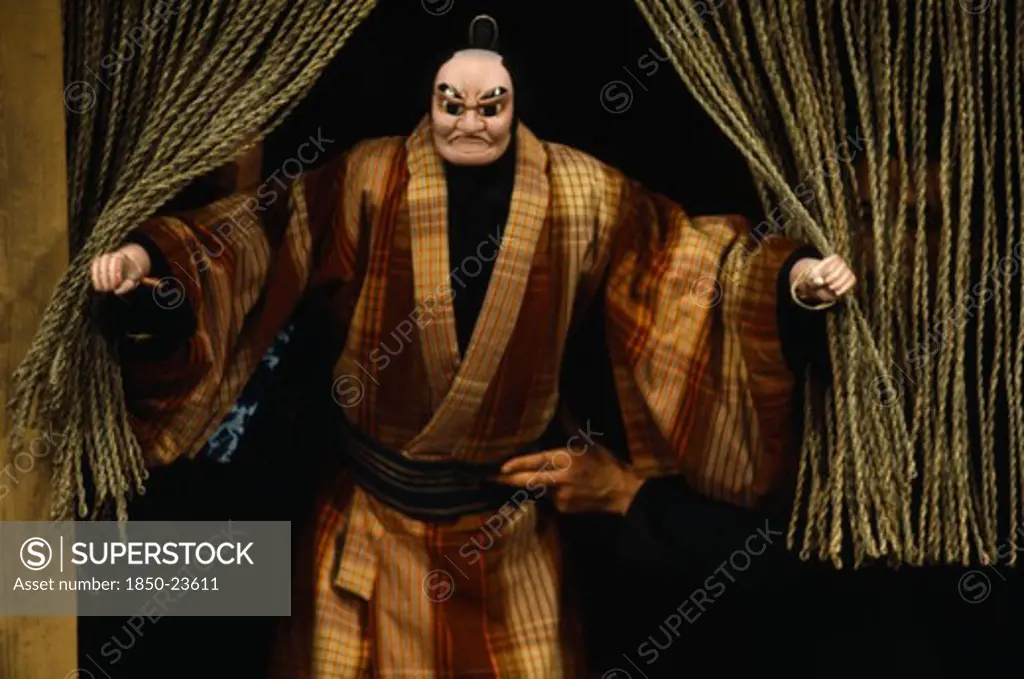 Japan, Arts, Performance, Bunraku Puppet Male Character Appearing From Behind Curtains With Puppeteer Partly Seen At Side.