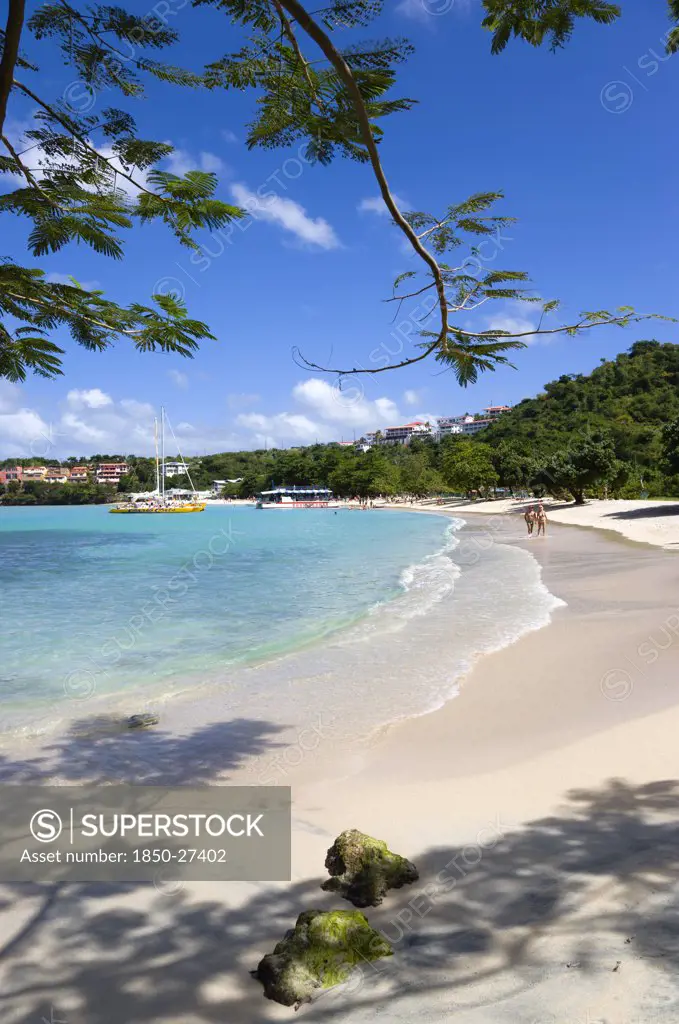 West Indies, Grenada, St George, Gentle Waves On Bbc Beach In Morne Rouge Bay With Tourists In The Sea On The Beach And Aboard Their Tour Catamaran In The Aquamarine Water.