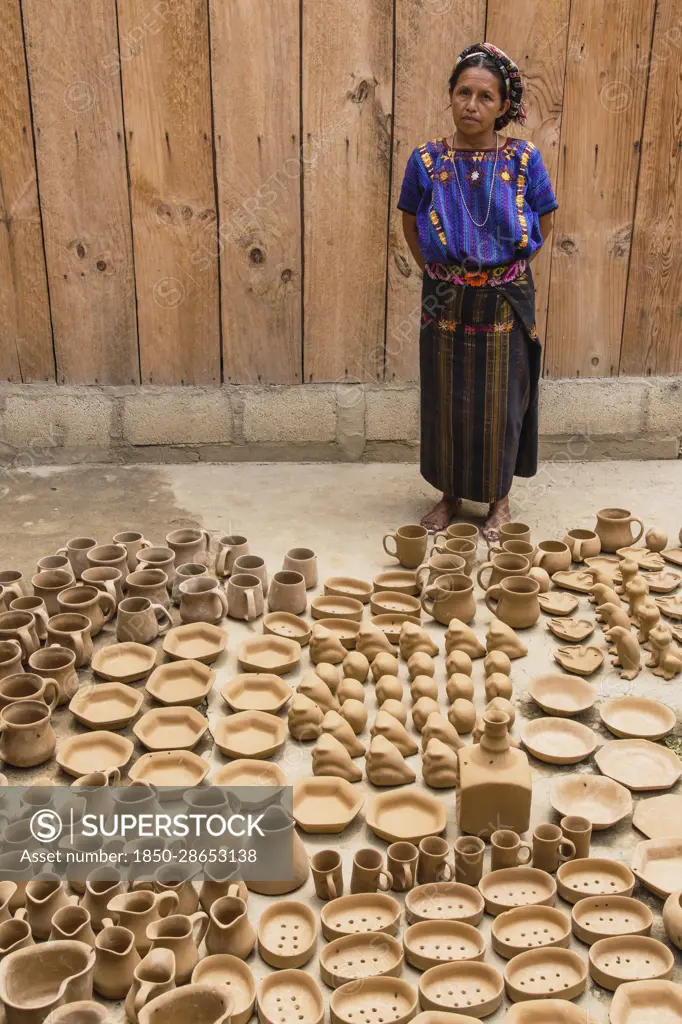 Guatemala, Solola, San Antonio Palopo, A Cakchiquel Mayan woman at her pottery workshop in the traditional dress including the elaborate cinta or hair wrap, woven blue huipil blouse, faja or belt, and corte skirt.