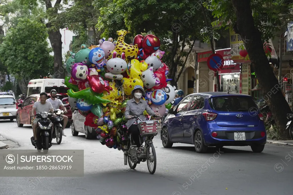  Vietnam, Hanoi, Balloon seller on moped. 