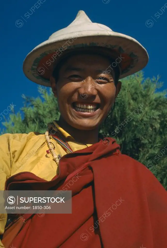 Tibet, Lhasa, Portrait Of Smiling Monk Wearing Hat