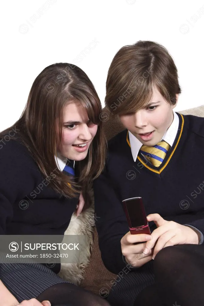 Children, Teenagers, Girls, Teenage girls in school uniform texting on a mobile phone.