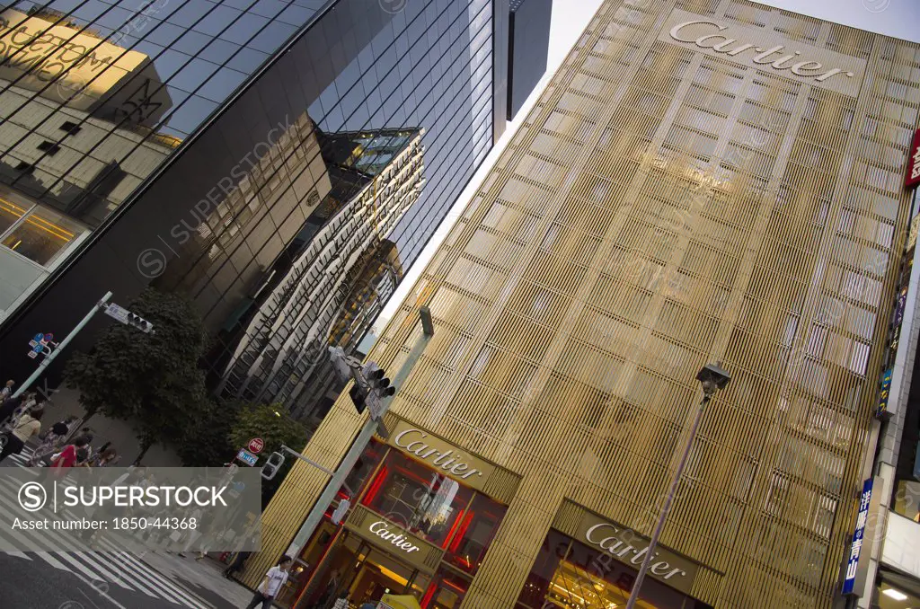 Japan, Honshu, Tokyo, Ginza Golden facade of the Cartier Building with the Chanel Building on left and DeBeers curved facade reflected in black glass on Chuo-dori Avenue.