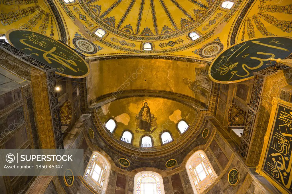 Sultanahmet Haghia Sophia with apse mosaic of Theotokos or Virgin Mary enthroned holding the baby Jesus Christ below the dome and Arab Muslim texts on Calligraphic Roundels on the walls.Turkey Istanbul