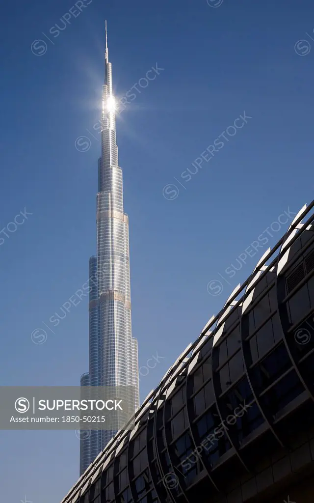 UAE, Dubai, Mall walkway over highway in front of Burj Khalifa tower.