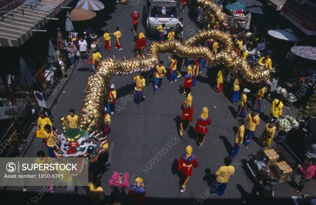 Thailand, North, Chiang Mai, Chinese New Year.  View Looking Down On Dragon Dance And Watching Crowds Under Striped Awning And Sun Umbrellas Lining Road.