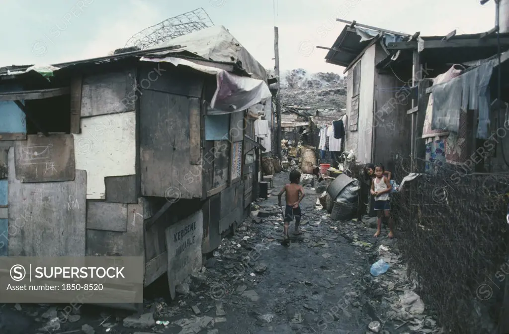 Philippines, Luzon Island, Manila, Smokey Mountain Slum Area.  Children In Narrow Alleyway Between Dilapidated Shacks.