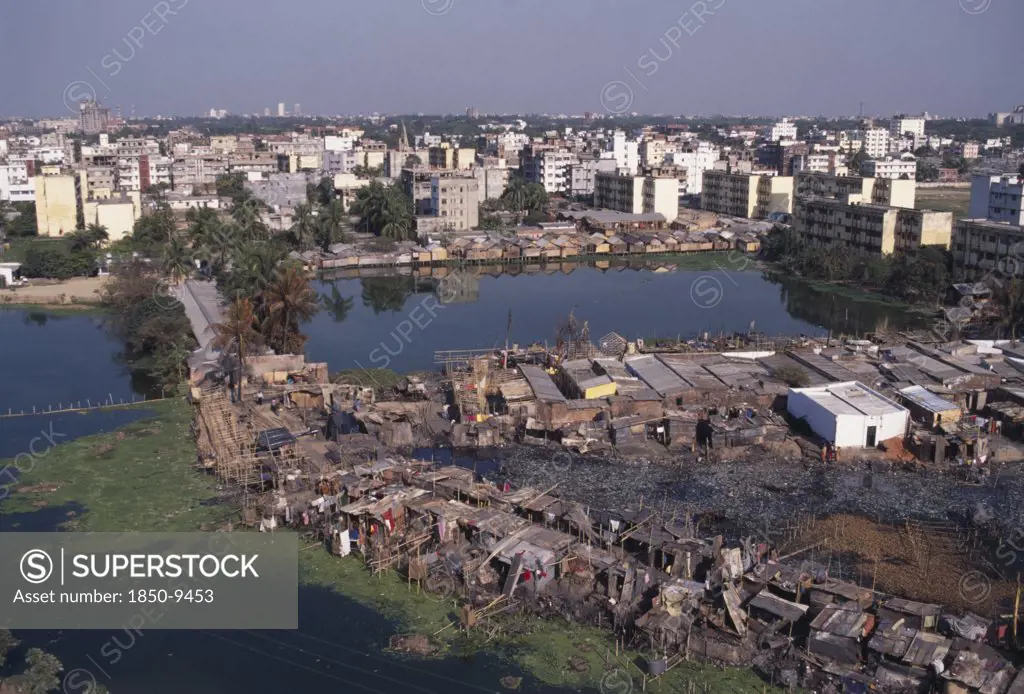 Bangladesh, Dhaka, Waterside Slum Dwellings After Fire With City Buildings Beyond.