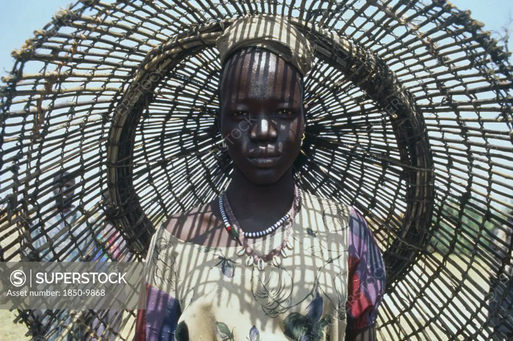 Sudan, Bahr El Ghazal, Portrait Of Young Dinka Woman With Fishing Basket Behind Her Casting Shadow Pattern Over Her Face And Upper Body.