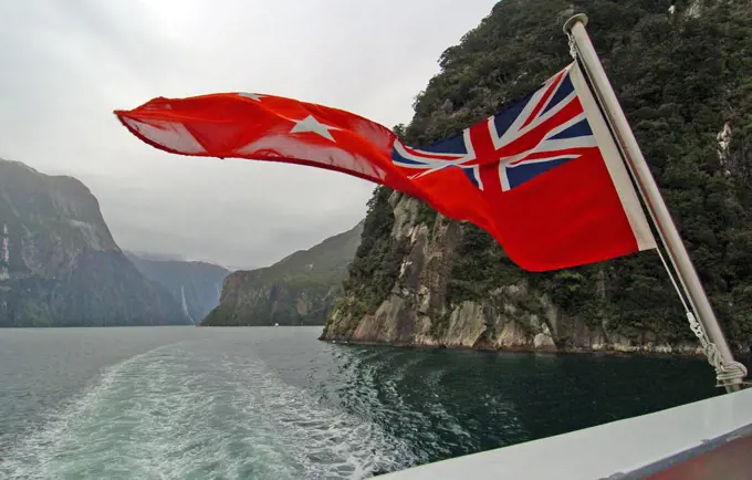 New Zealand, South Island, 'Milford Sound,', 'Southland, A New Zealnd Ensign Flag Waves On The Rear Of Real Journeys Cruise Boat The Milford Mariner As It Travels Along Milford Sound In New Zealands Fjordland Area'