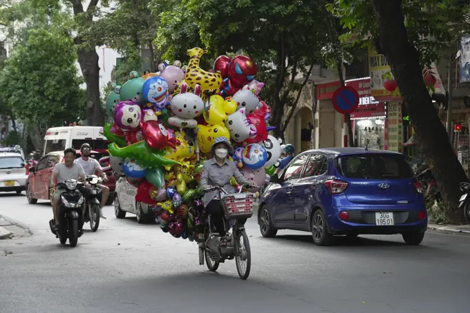  Vietnam, Hanoi, Balloon seller on moped. 