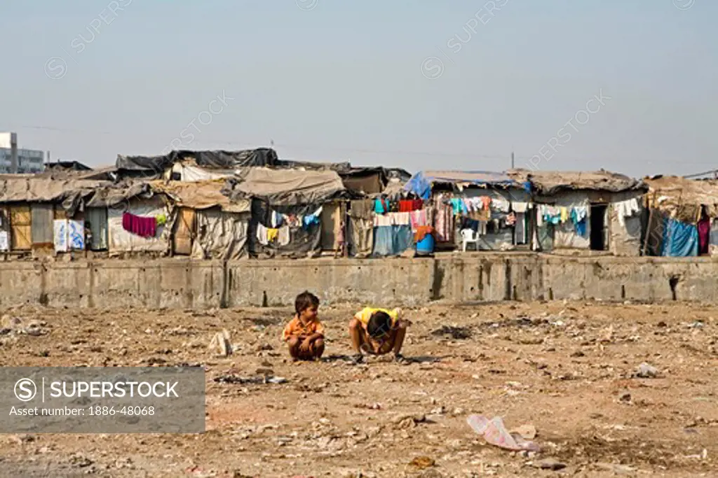 Children defacing surrounding of slum by using area as open toilet ; Bombay Mumbai ; Maharashtra ; India