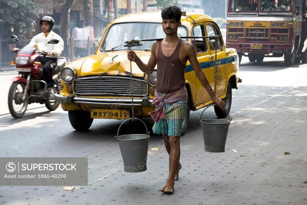 Man carrying water on shoulder in two buckets ; Park street ; Calcutta now Kolkata ; West Bengal ; India