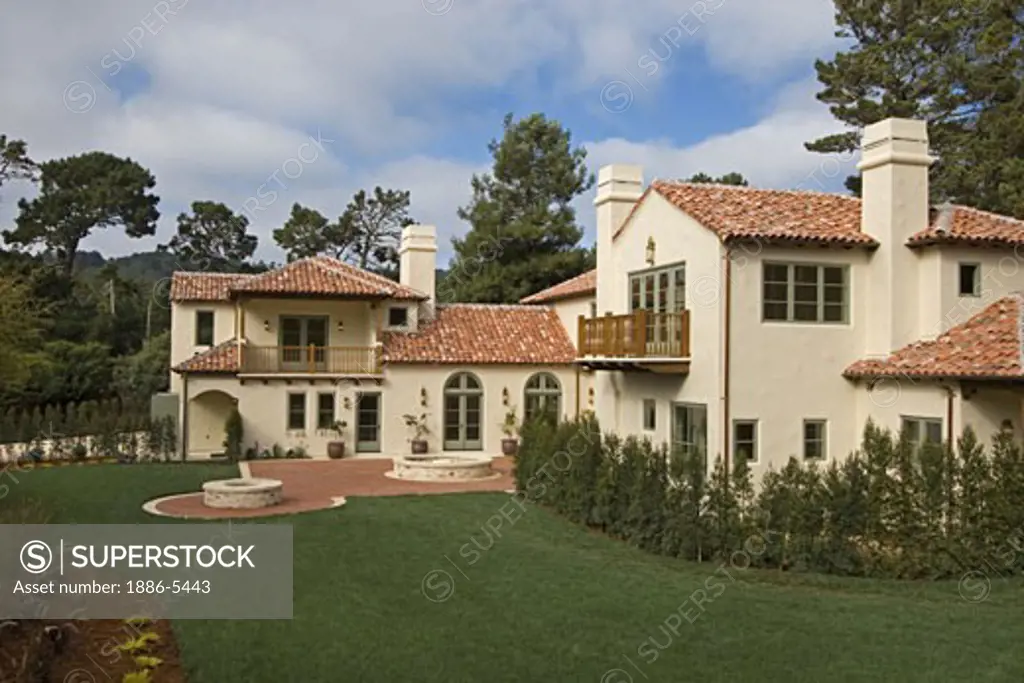 Exterior of a SPANISH STYLE LUXURY HOME with stucco walls and red tile roof 