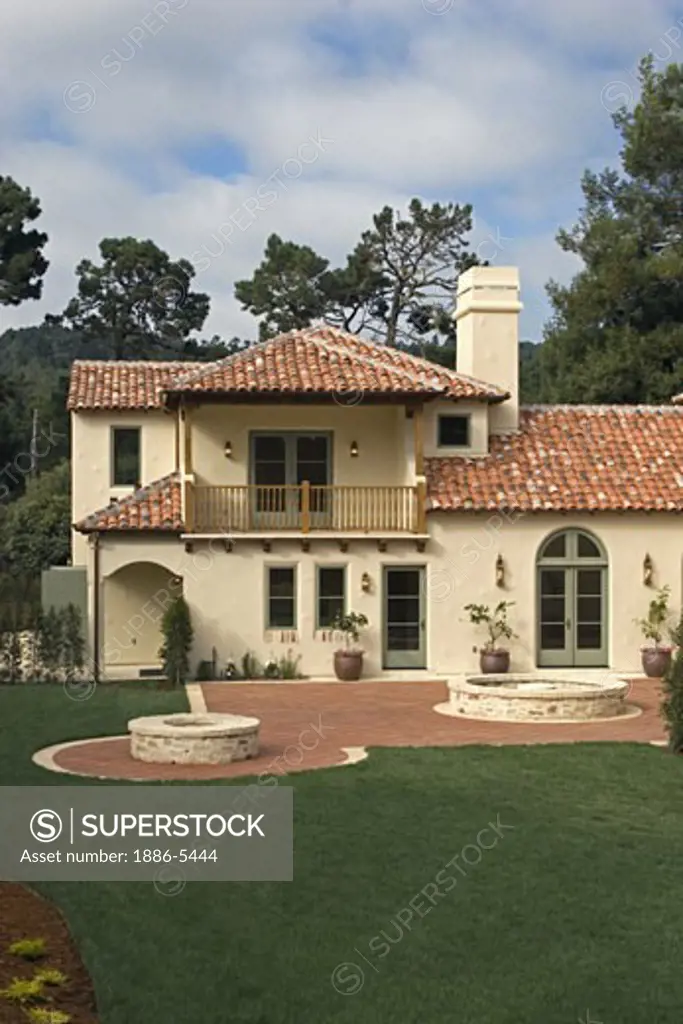 Exterior of a SPANISH STYLE LUXURY HOME with stucco walls and red tile roof 