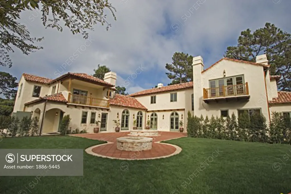 Exterior of a SPANISH STYLE LUXURY HOME with stucco walls and red tile roof 