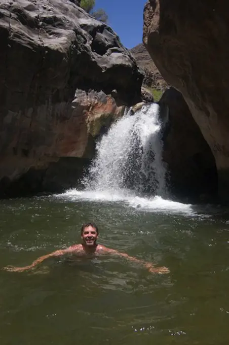 Raft guide Todd Lovell enjoys a swim below the waterfall at SHINOMU CREEK  at mile 108 along the Colorado River - GRAND CANYON, ARIZONA