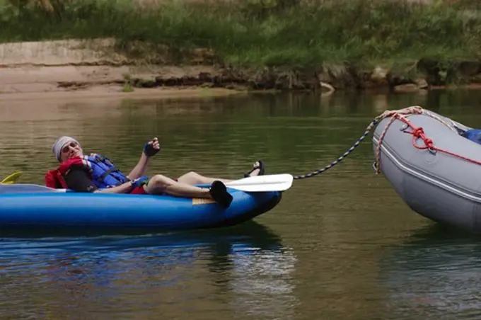 A rafter relaxes in an INFLATABLE KAYAK along the Colorado River - GRAND CANYON,  ARIZONA