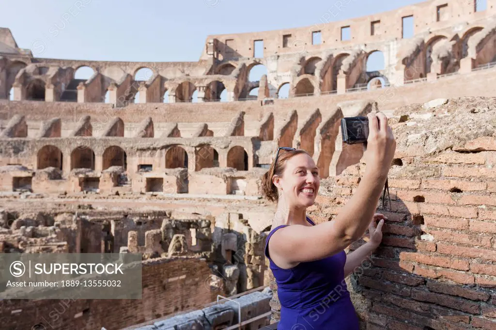 A young female tourist takes a selfie with her camera at the Roman Colosseum; Rome, Italy