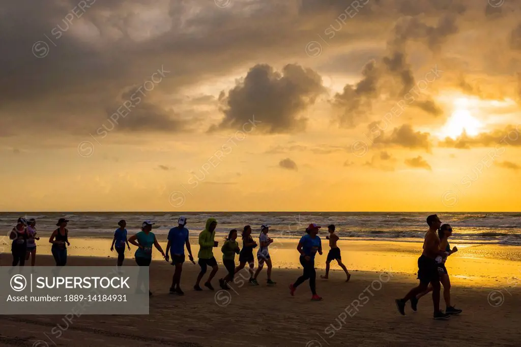 Runners race on the beach at sunrise during the 2017 USA Beach Running Championships; Cocoa Beach, Florida, United States of America