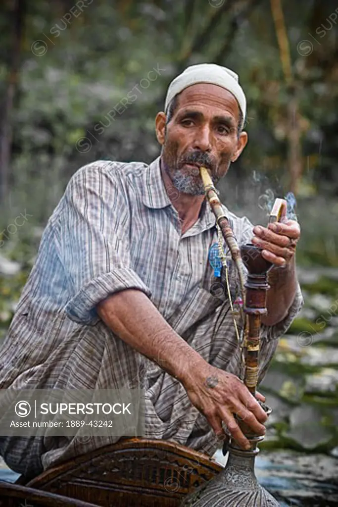 Dal Lake, Srinagar, Kashmir, India; Man smoking hookah pipe