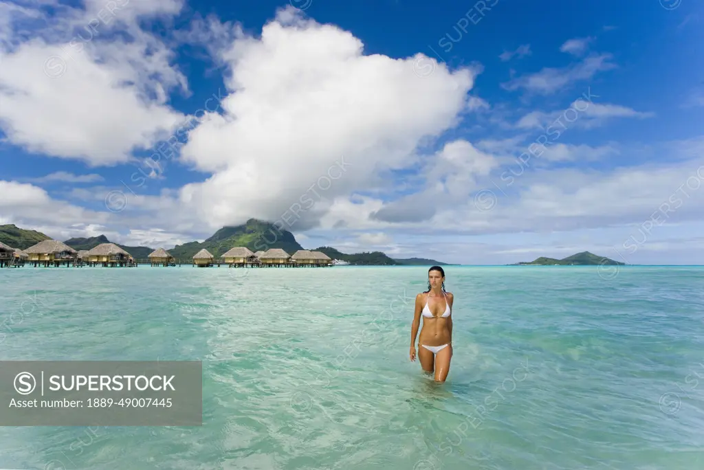 French Polynesia, Tahiti, Bora Bora, Woman In The Ocean With Bungalows In The Background.