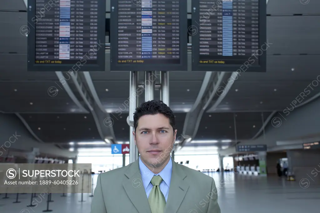 Businessman At Airport In Front Of Flight Information Monitors, Toronto, Ontario, Canada