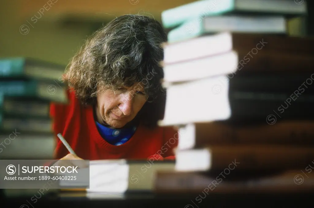 Woman Writing With Stacks Of Books