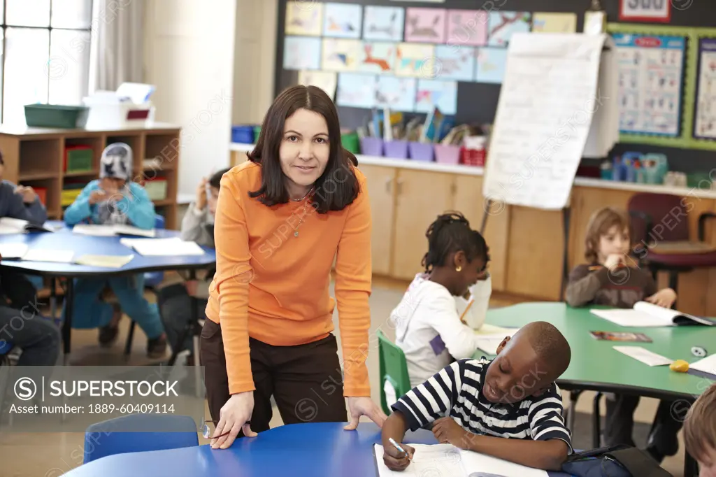 Teacher Helping Young Grade 3 Boy At His Desk In Classroom; Toronto Ontario Canada