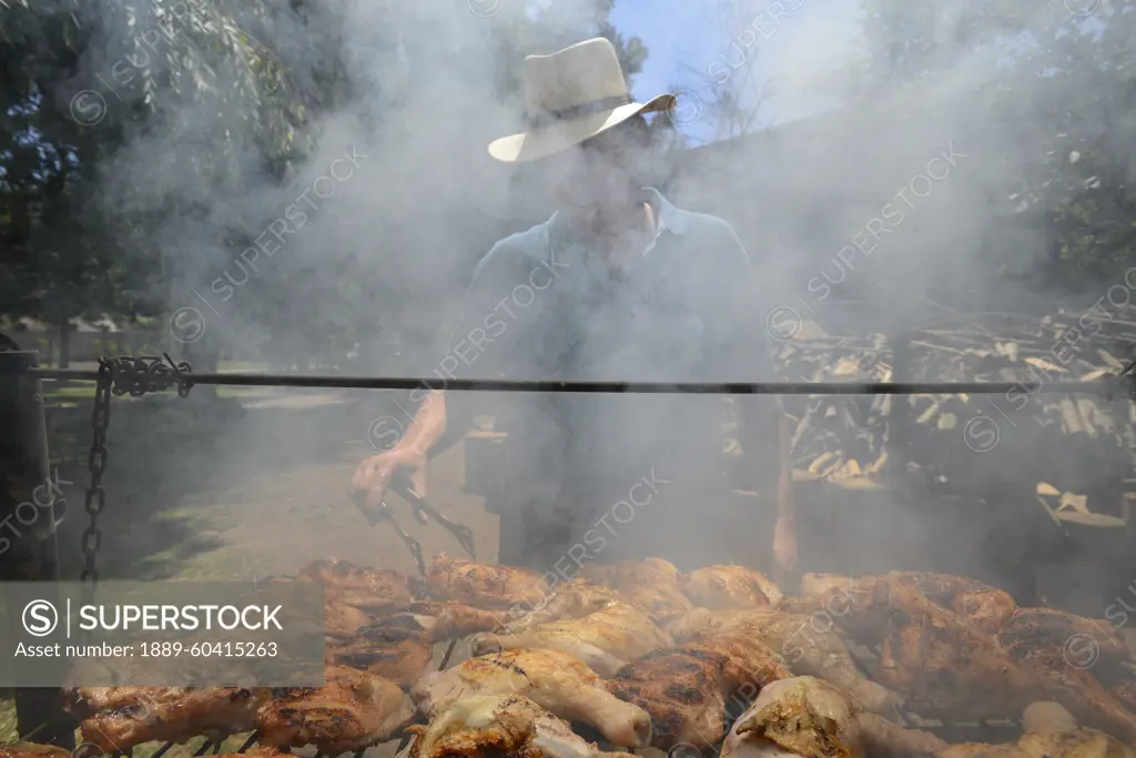 Man in smoke over a large barbecue in Chile; Santiago de Chile, Chile