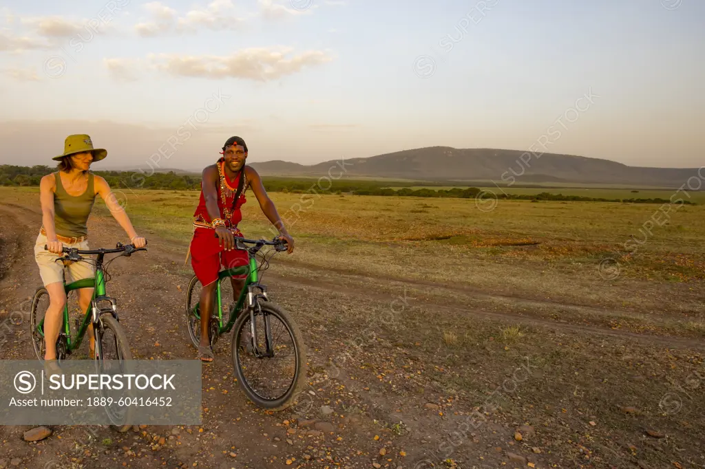 Tourist with guide on mountain bike safari in the Maasai Mara National Reserve, Kenya, Africa; Maasai Mara, Kenya