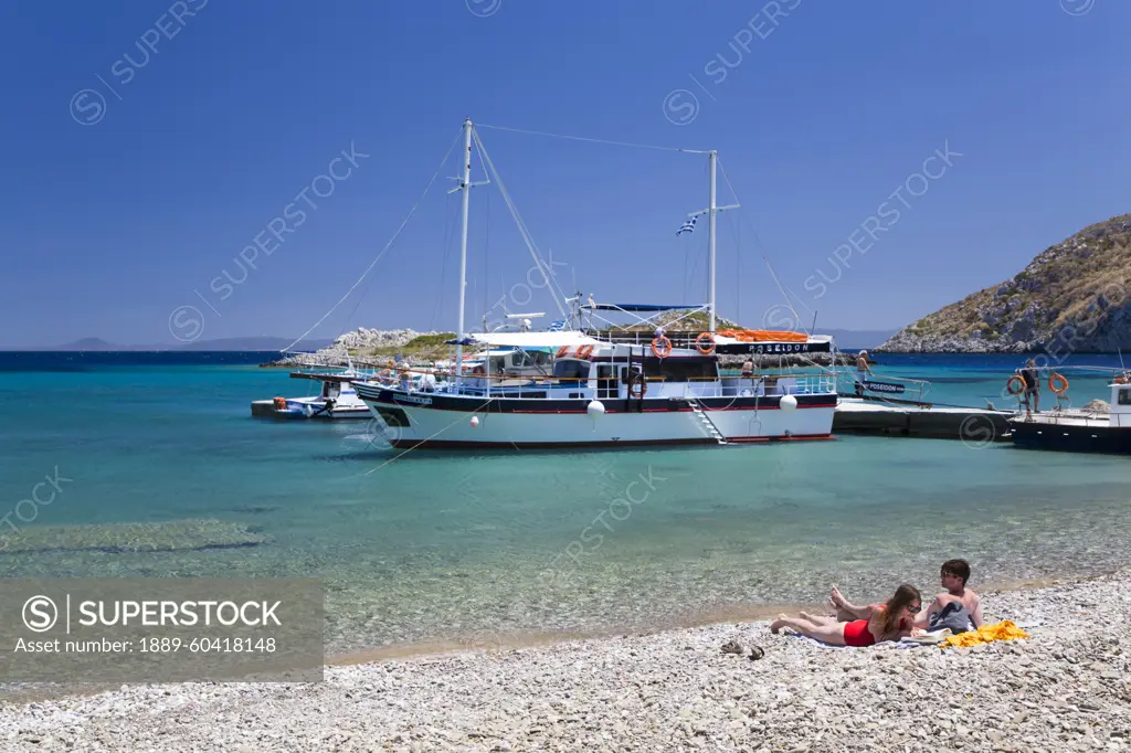 Sunbathers enjoying Sesklia Beach on Symi Island in Greece; Symi, Dodecanese, Greece