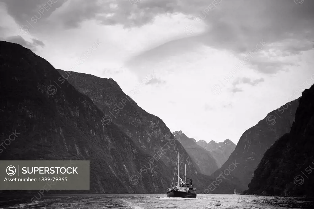 A Boat Travels Through A Waterway Between The Mountains, Milford Sound South Island New Zealand