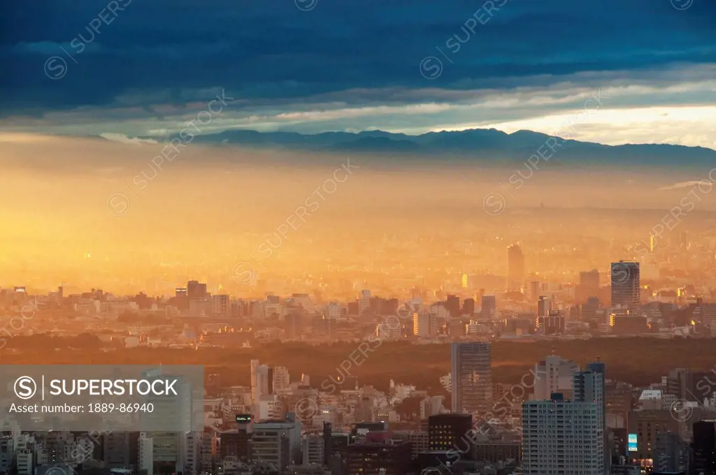 Japan, Sunlight At Sunrise Over Cityscape With Mountains In Background; Tokyo