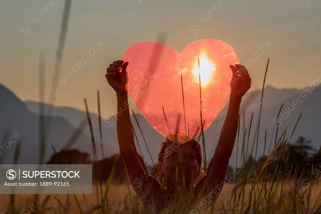 A Woman Holds Up A Red Heart With The Sun To Shine Through; Locarno, Ticino, Switzerland