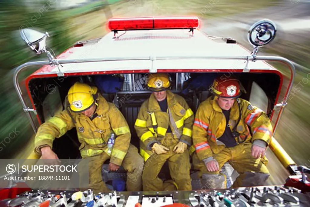 Firemen riding on back of fire truck