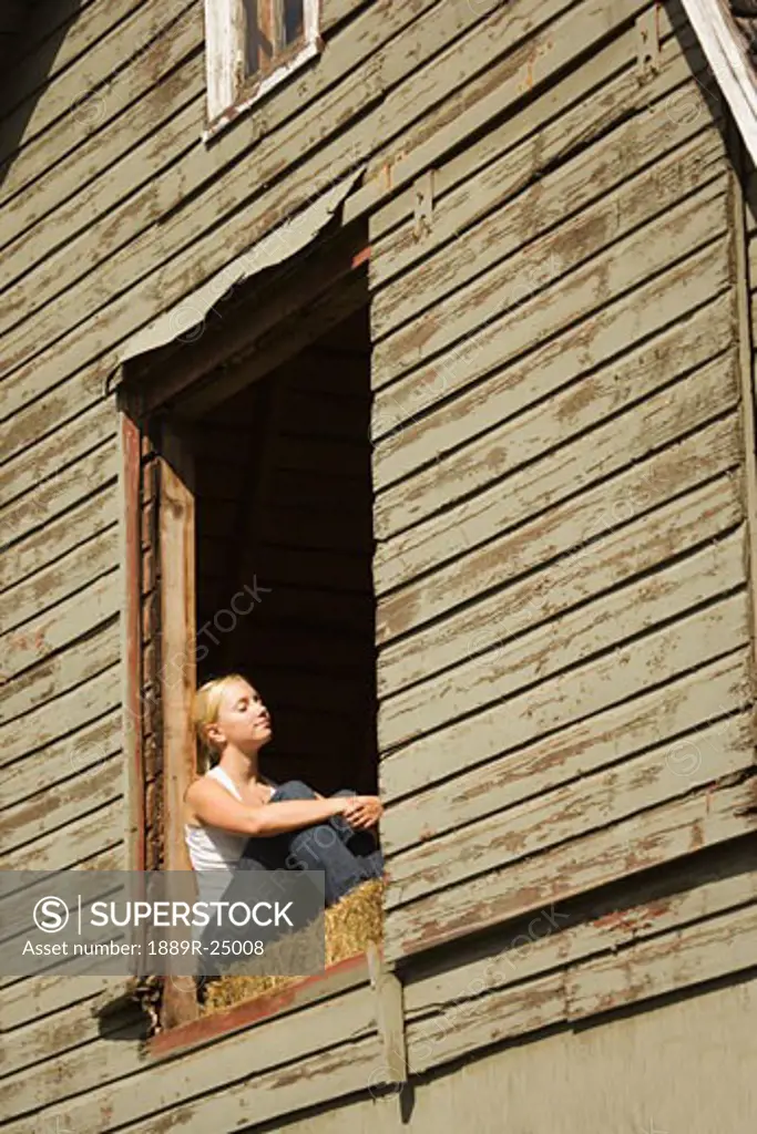 Young woman sitting in barn loft