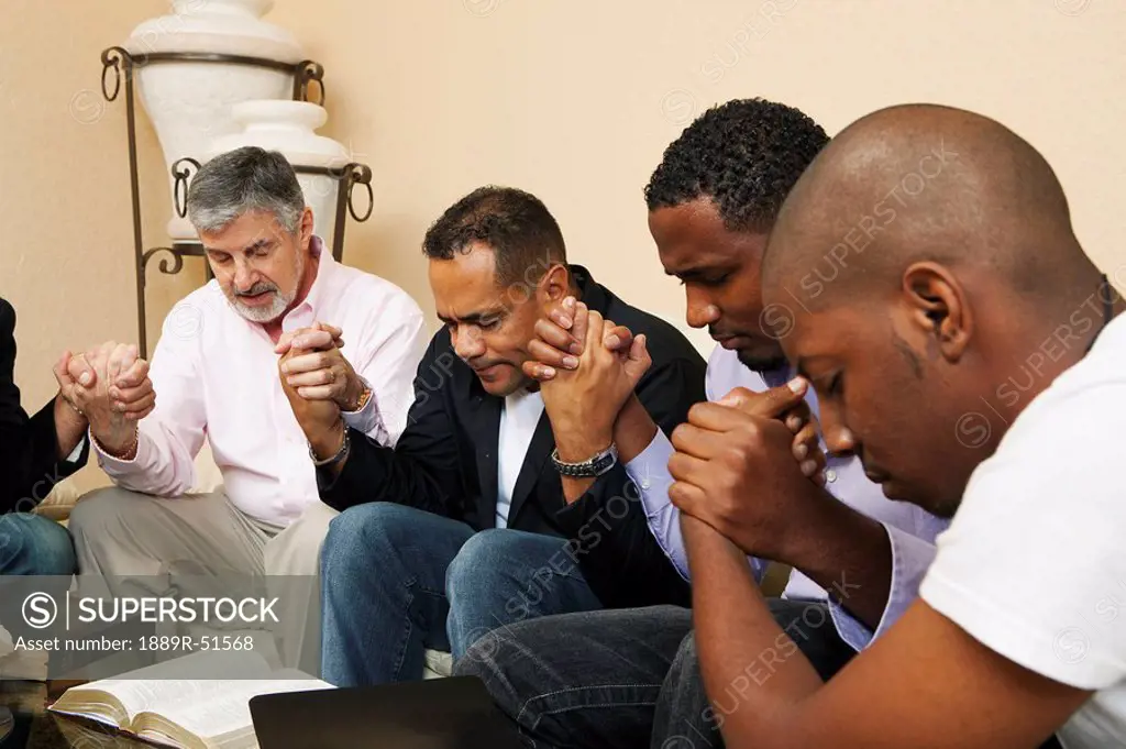 a group of men praying together with an open bible