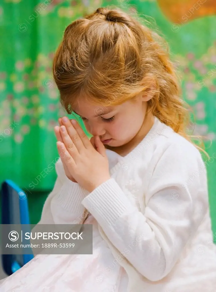 a young girl bowing her head in prayer