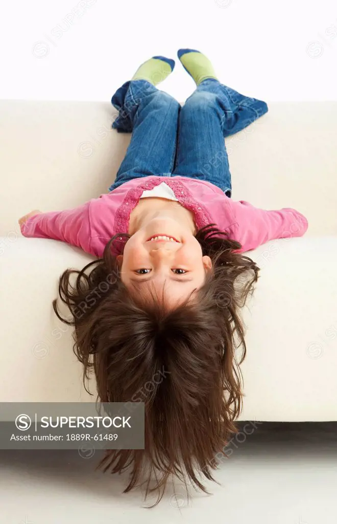 A Girl Hanging Upside Down From The Couch