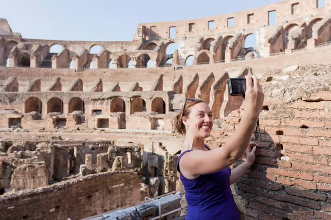 A young female tourist takes a selfie with her camera at the Roman Colosseum; Rome, Italy