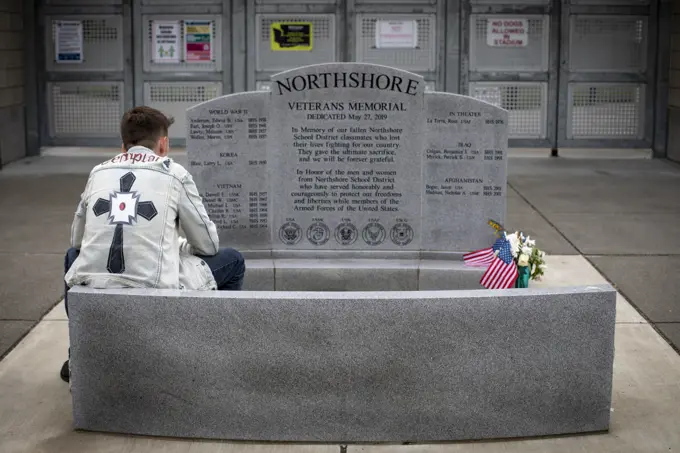 Young man sits in contemplation at an America war veterans memorial; Bothell, Washington, United States of America