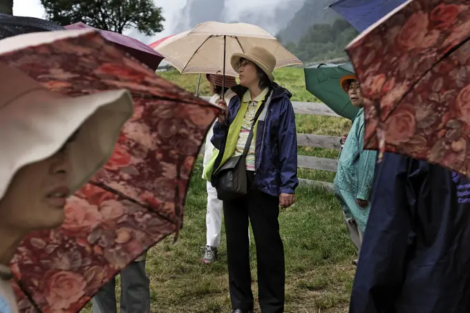 Japanese tourists under umbrellas at Heidiland, home of the fictional character Heidi