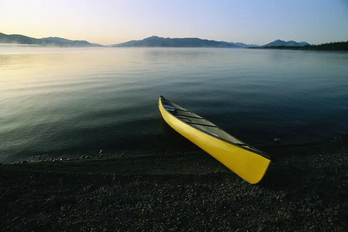 Yellow canoe on the shore of a calm body of water, Kluane Lake, Kluane National Park, Yukon, Canada; Yukon, Canada